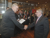 TEAM:n puheenjohtaja Timo Vallittu luovuttaa liiton kultaisen ansiomerkin Vesa Pernalle